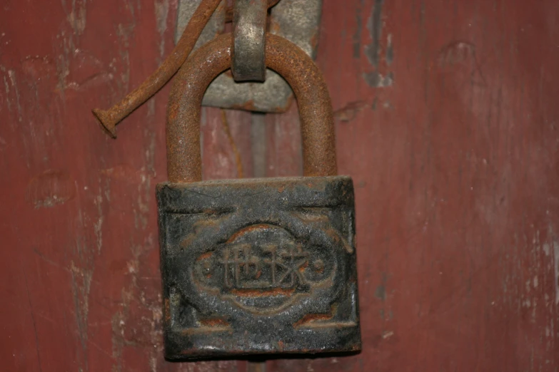 a rusty padlock hangs on the side of an old door