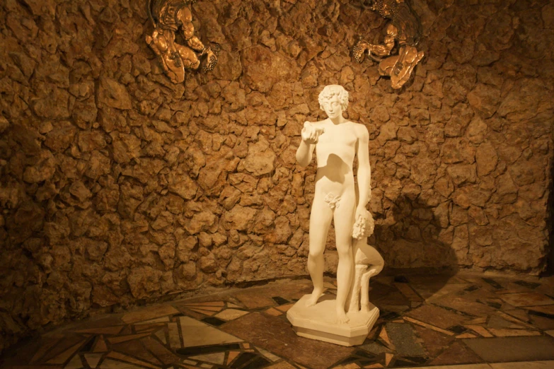 an art sculpture of a young man next to a stone wall