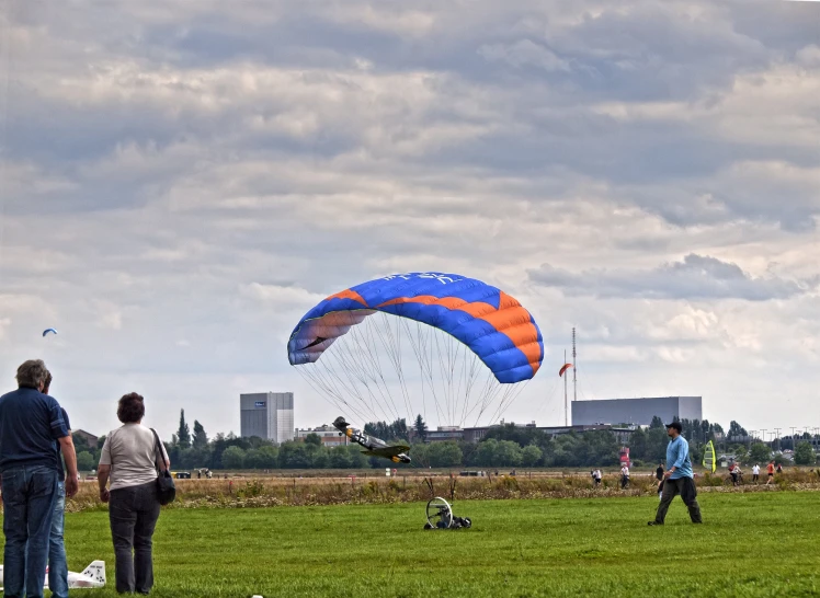 group of people standing in field flying large kite