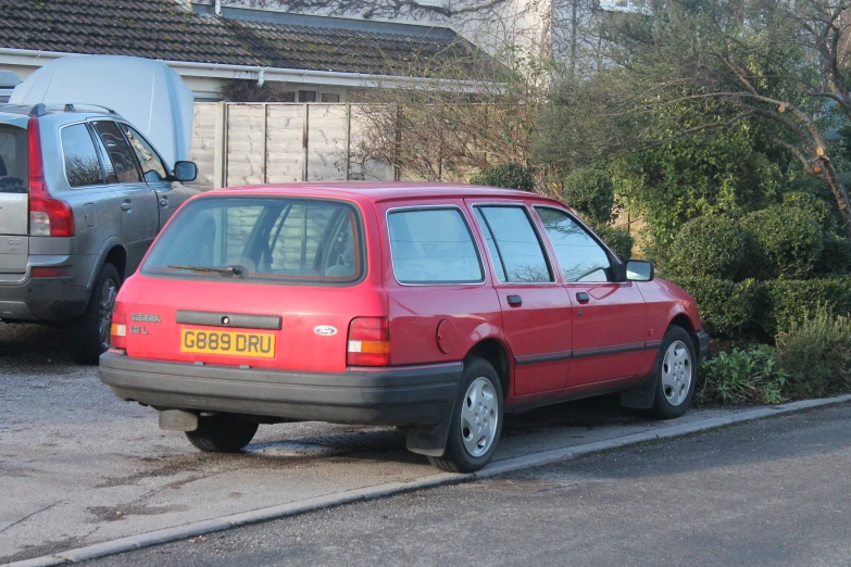 red car parked on the side of a street next to a house