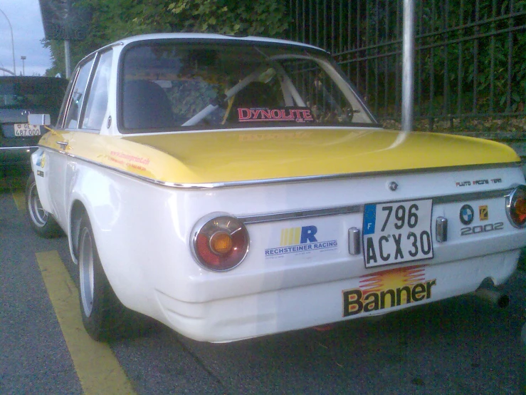 an old white and yellow car is parked