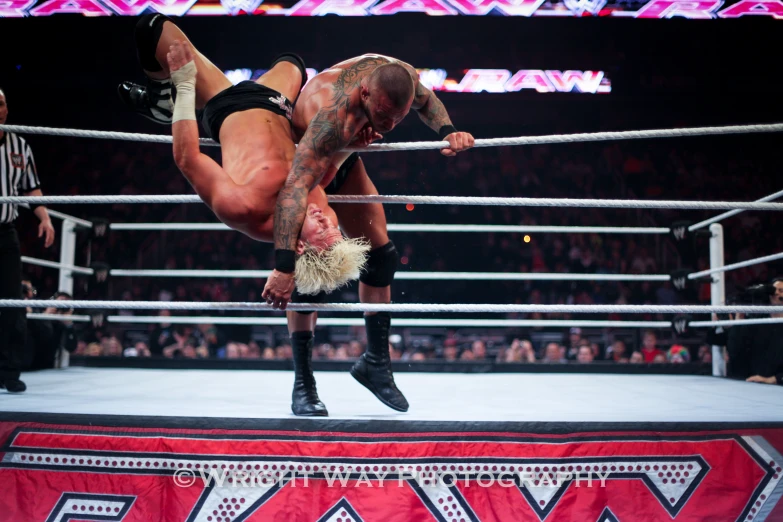 a wrestler on one leg hanging from the side of a pole