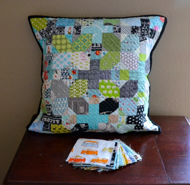 a patchwork pillow with various patterns and fabrics on a side table