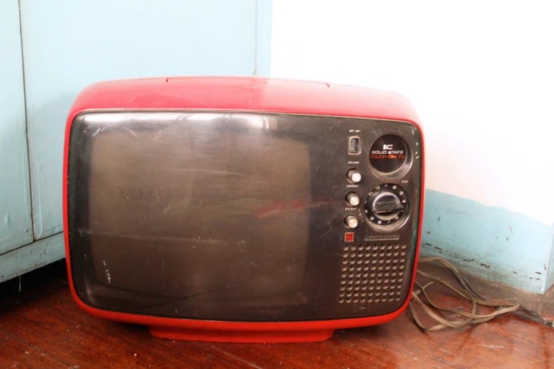 a red and black television on a brown wooden floor