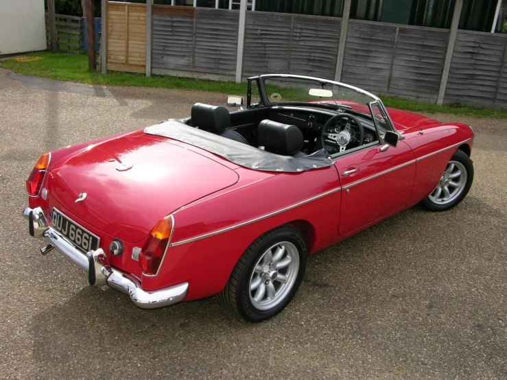 an old model red sports car parked in a lot