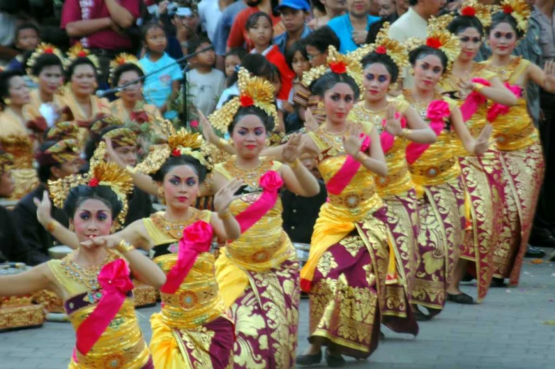 girls in gold and red dresses with pink leis doing dance