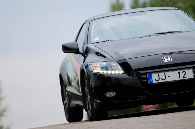 a black car driving on the road with its lights on