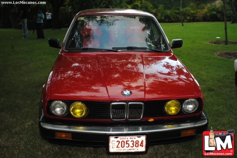 a red car parked next to some trees and grass