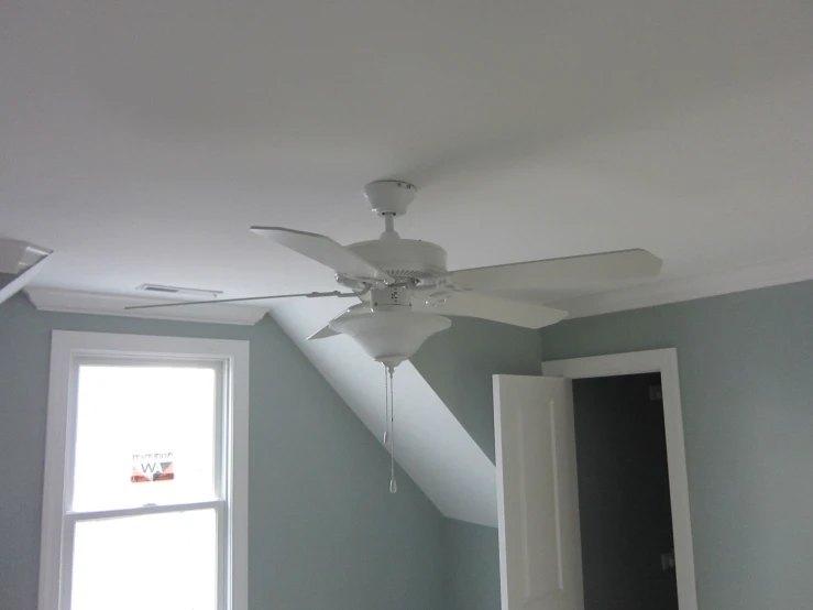 an empty bedroom with a ceiling fan in the corner