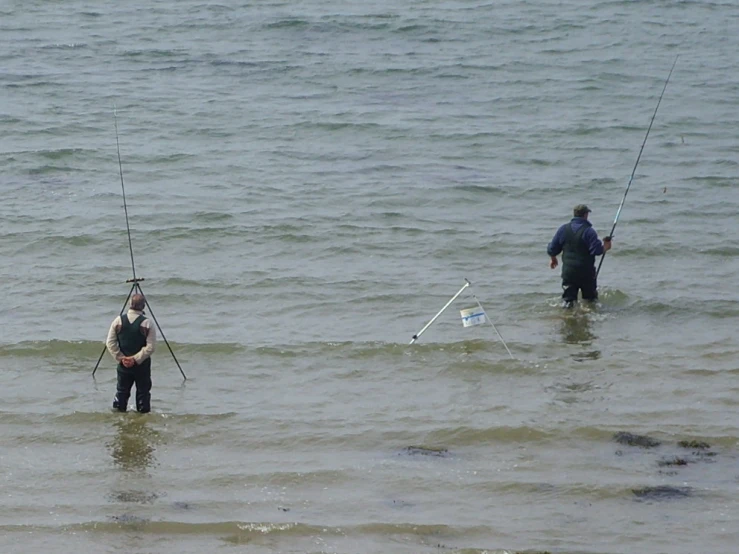two men who are standing in the water with fishing rods