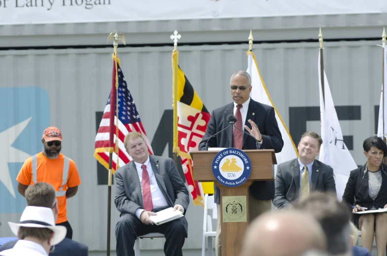 two men wearing suits and tie standing at a podium