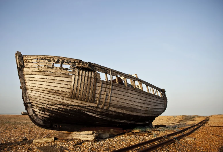 an abandoned boat on the side of the sand