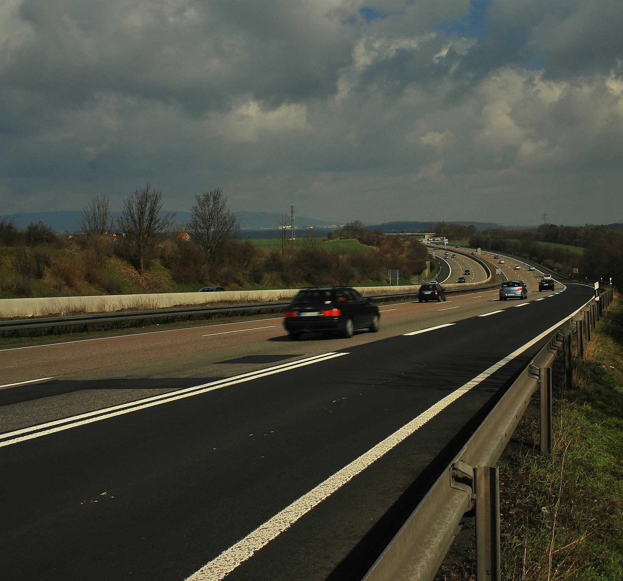 two cars on a freeway with a stormy sky