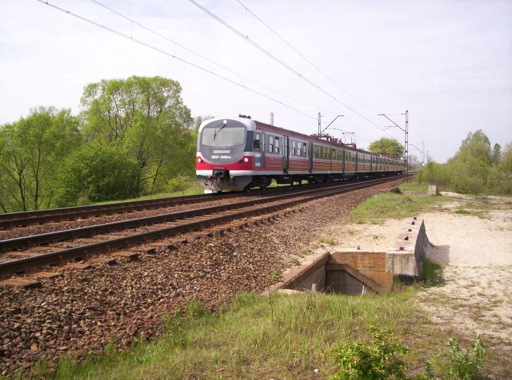 a red and white train traveling along train tracks