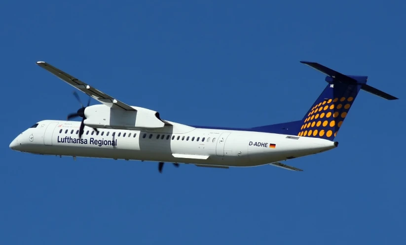 a jetliner flying through the blue sky with lots of orange dots