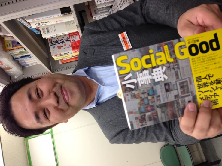 a man with an asian business suit and tie holding a yellow book