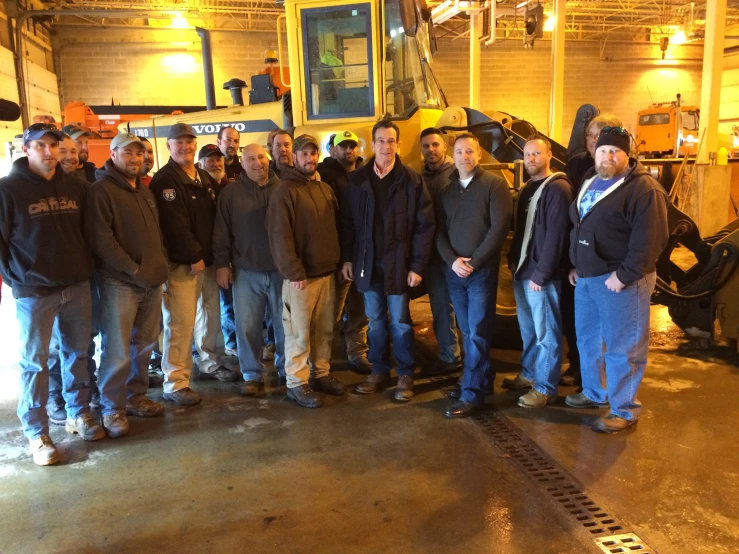 a group of men are posing together in front of a bulldozer