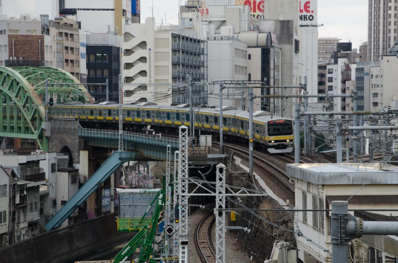 a train going across a bridge with lots of tall buildings behind it