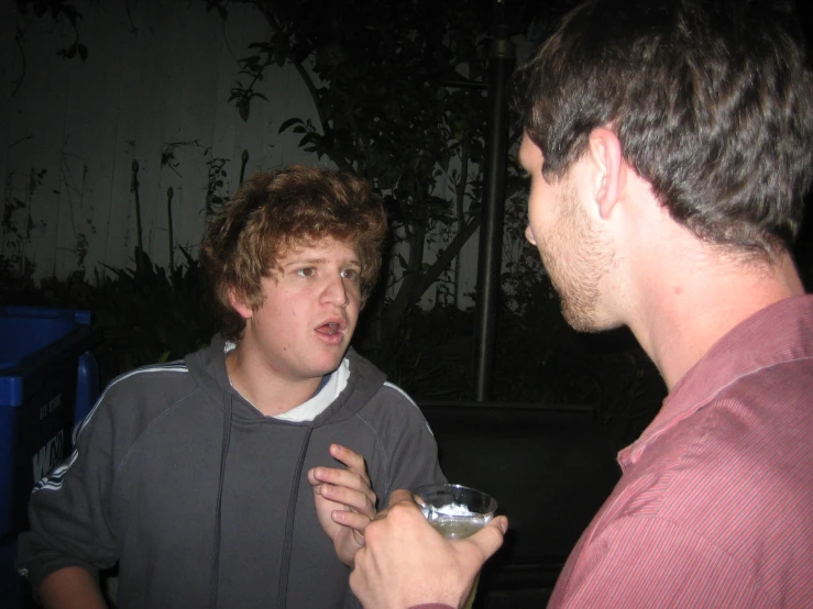 two men talking and drinking soing at night