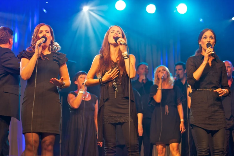 four beautiful young women singing in choir with microphones