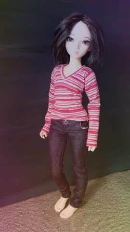 a doll with black hair wearing pink shirt and black pants