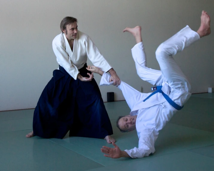 two men standing up in karate poses while one man attempts to balance