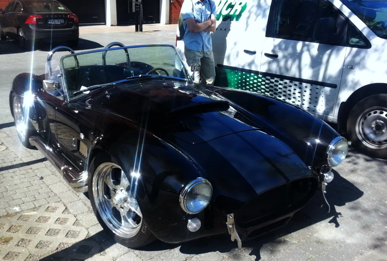 a vintage car sitting on the sidewalk in front of a van