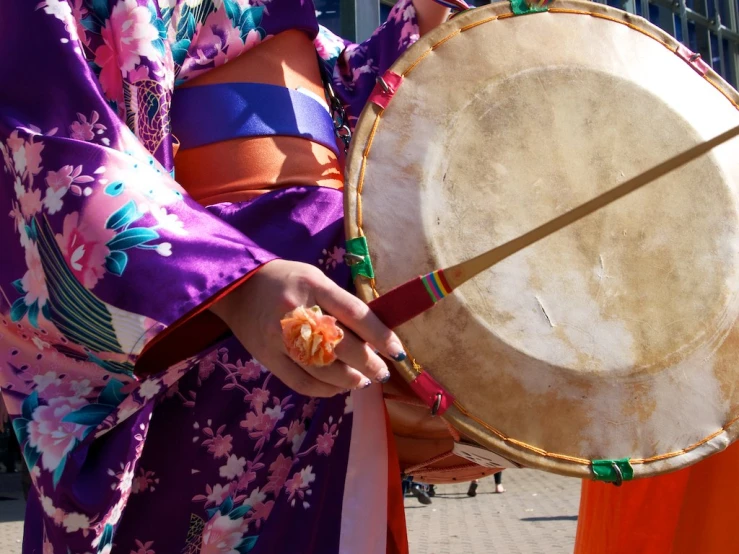 woman in oriental outfit holding a large drum