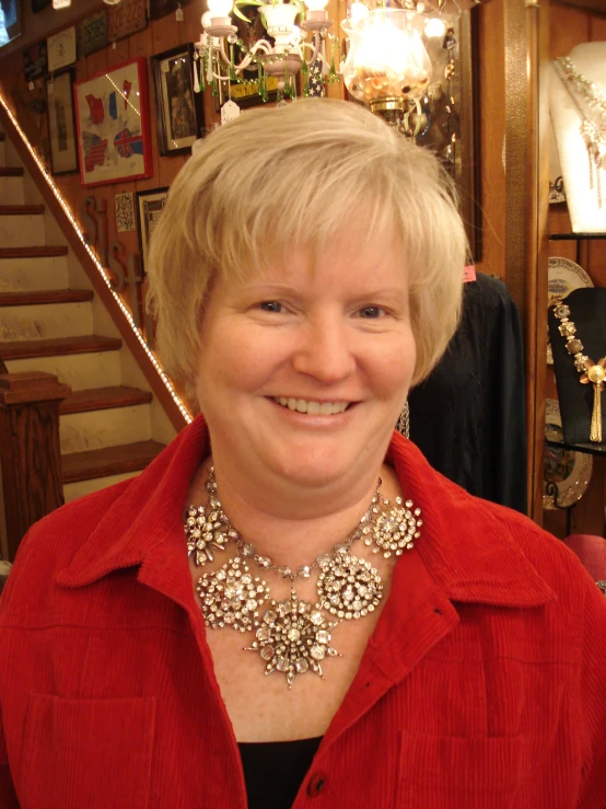 a smiling woman in a shop has necklaces on her head