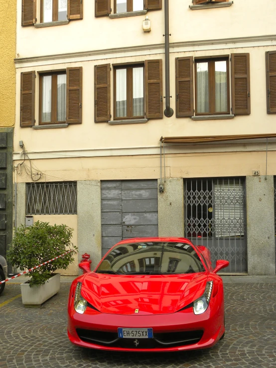 a large red sports car parked in front of a building