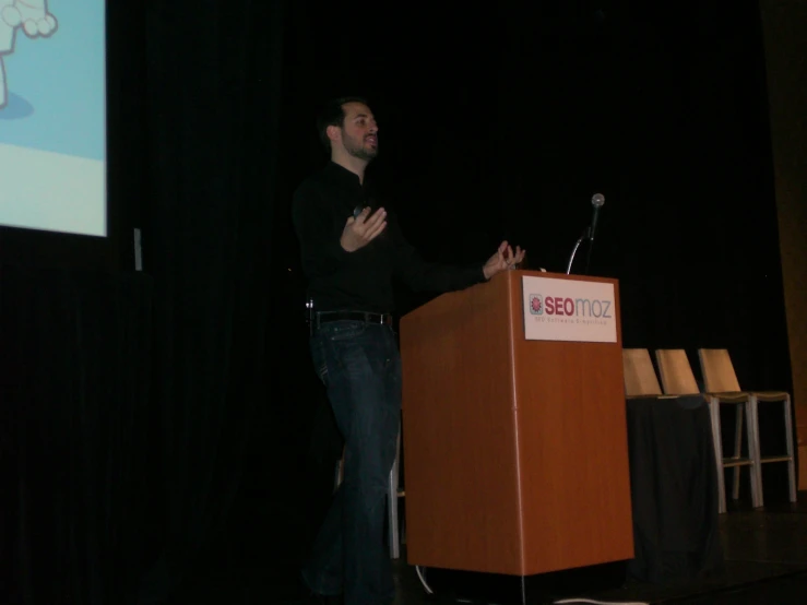 a man talking at a podium and gesturing