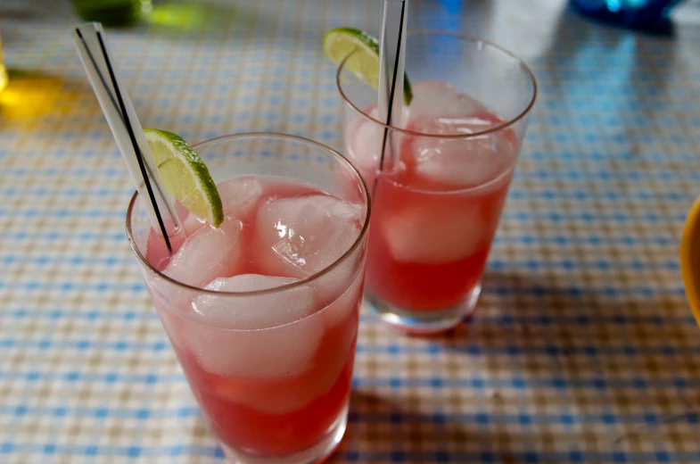 two small glasses of pink cocktail sitting on a table