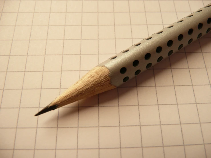 a wooden handled pencil laying on top of grid paper
