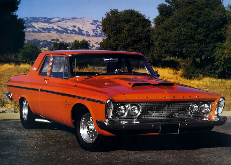 the old muscle car is red and parked in the lot