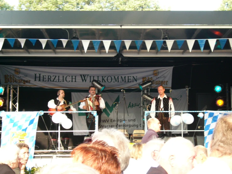 the group is singing on stage during an outdoor performance