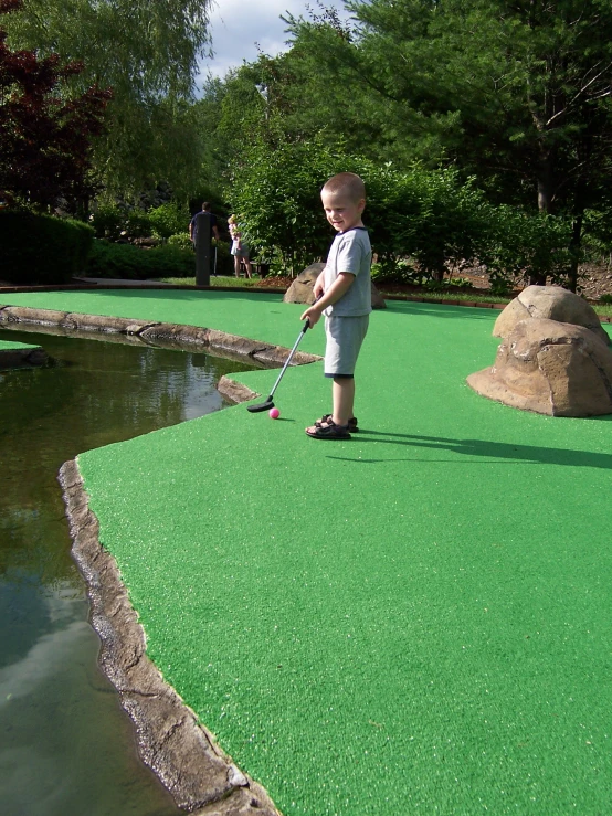 a baby boy in shorts playing mini golf