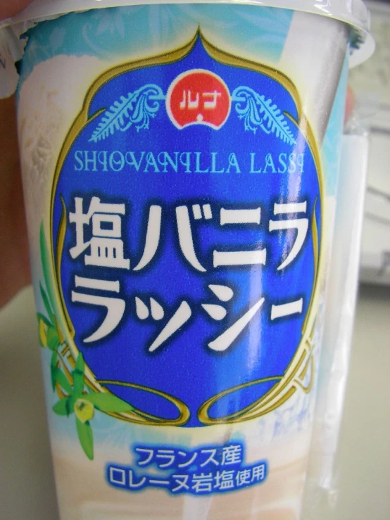 a bottle of yogurt with a person's hand reaching for the cup