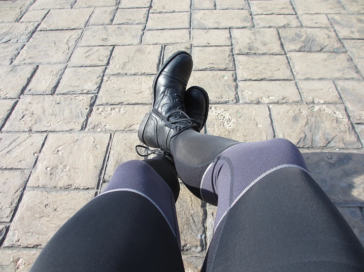 a person wearing black shoes stands on the sidewalk