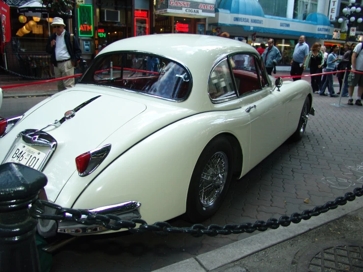 an old fashion white car is parked on the street