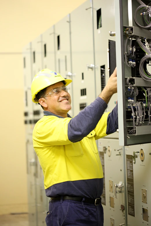 a man wearing a hardhat and hard hat working on an electrical panel