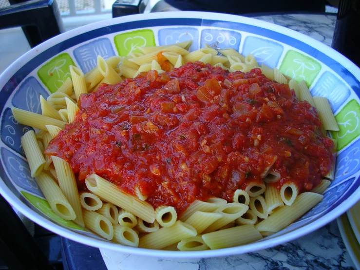 pasta and sauce in a blue white and green bowl