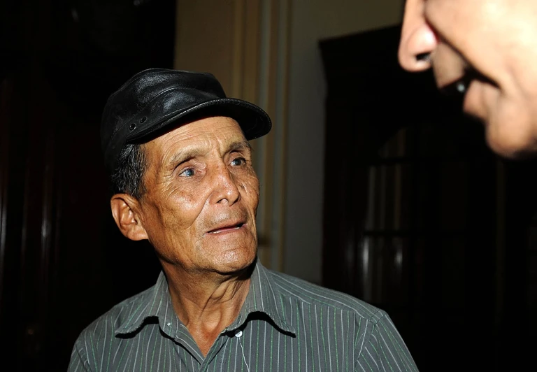 a older man in a striped shirt and black hat