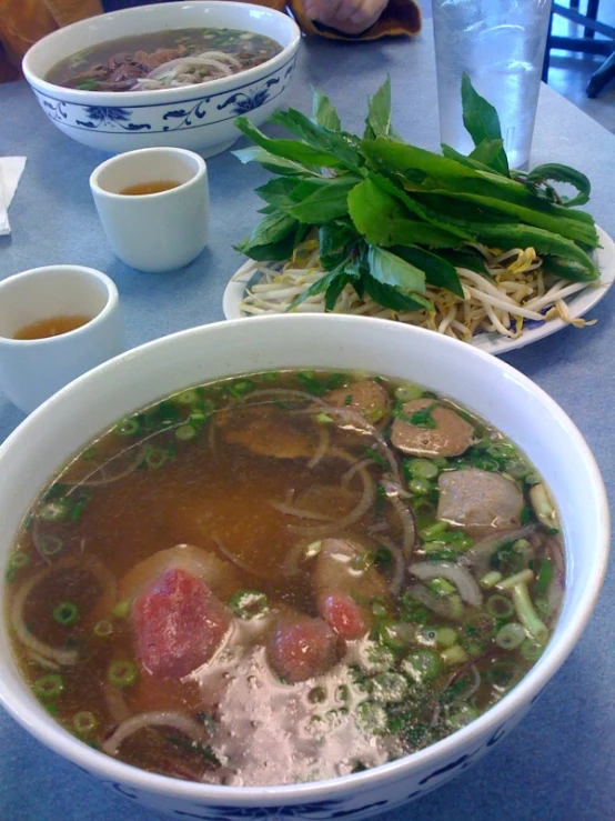 a bowl of  soup and bowls of vegetables on a table