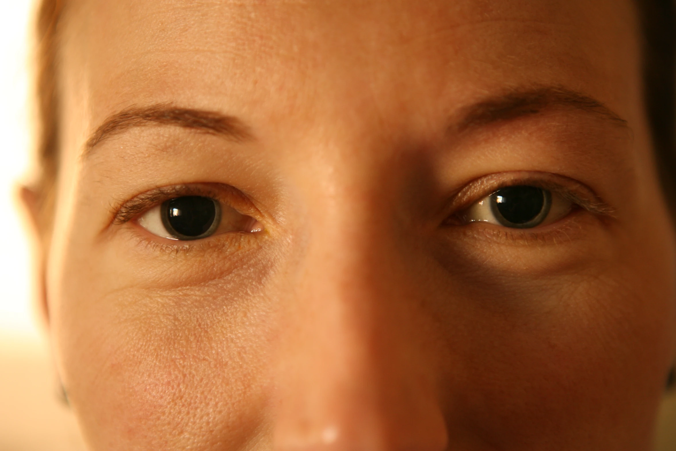 a close - up po shows one side of an adult's face with a thin line between her eye and the other half of an adult's face