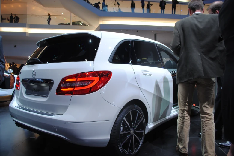 a man standing next to a white mercedes benz car