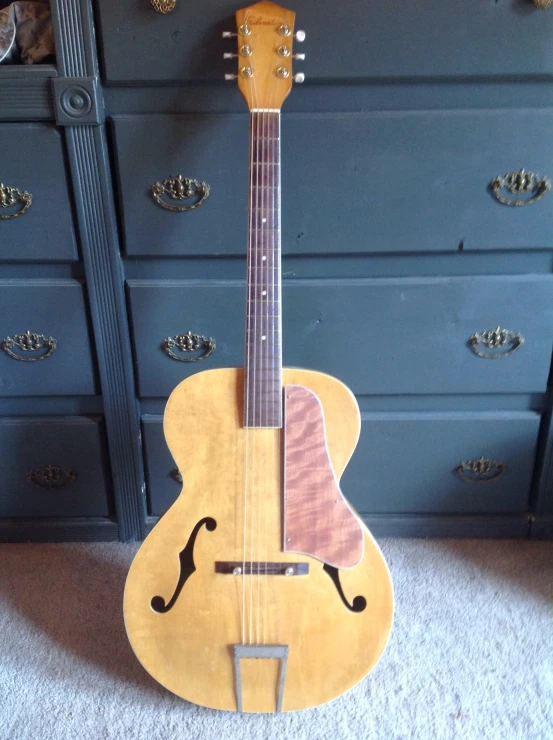 the old guitar sits by the blue dresser