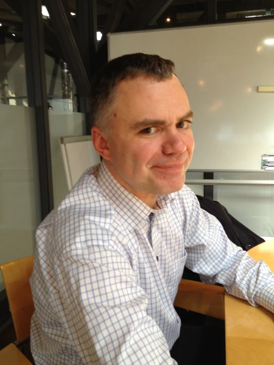 the man smiles while sitting at a table