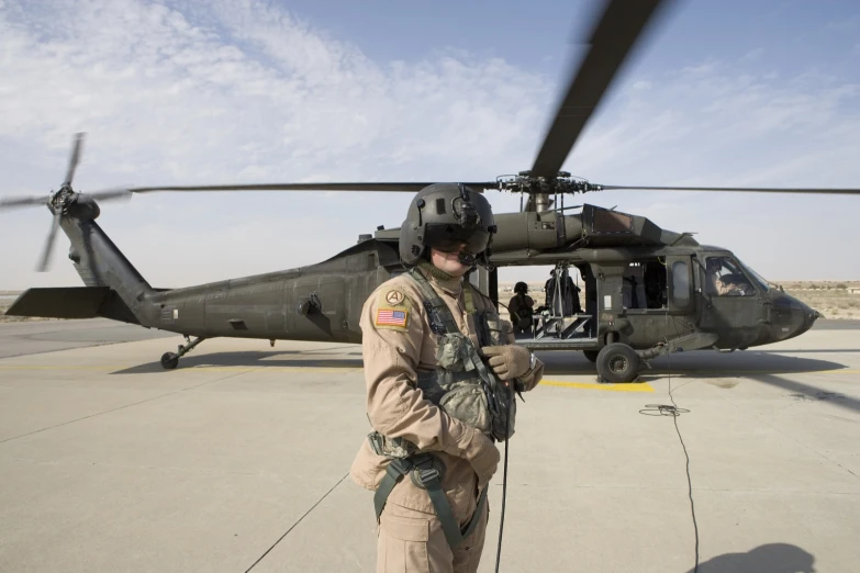 a man standing in front of an army helicopter on the runway