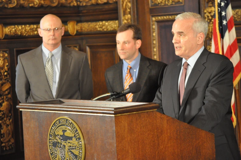 three men are standing at a podium with microphones