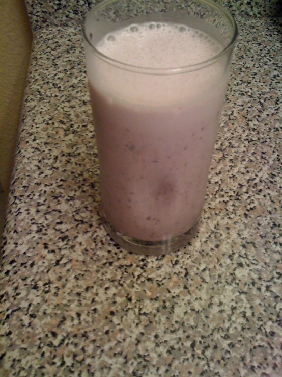 a glass with a blue drink inside of it on a counter